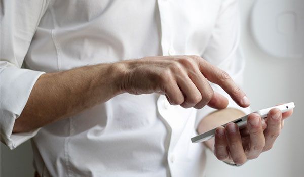 a man in a white shirt pressing on his mobile phone