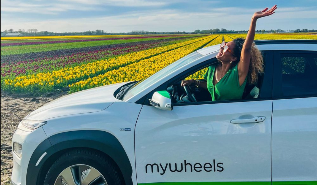 a woman happily driving a MyWheels ride sharing car