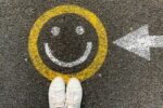 a happy face drawn in chalk on a sidewalk representing world happiness rankings