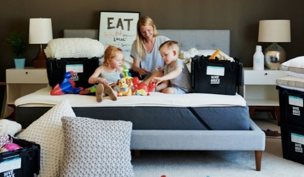 a mother and two kids sitting on the bed of a temporary monthly rental