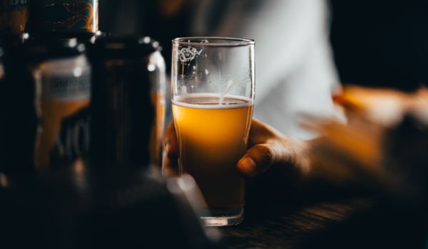 a hand holding a craft beer on a bar table