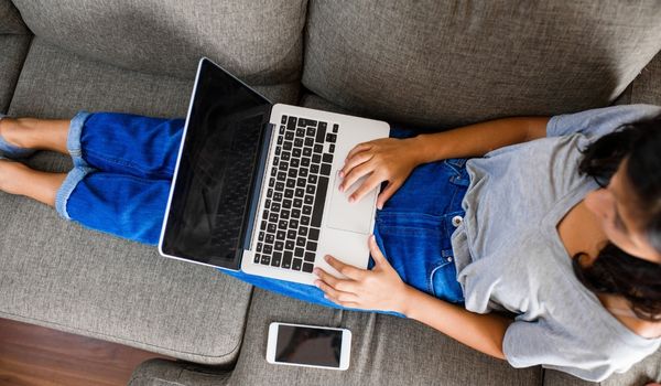 a woman recling on the couch at her computer studying the Inburgering changes