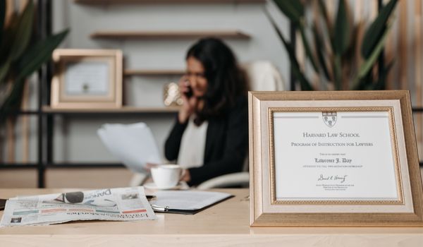 A woman sitting behind her desk with a diploma on the foreground