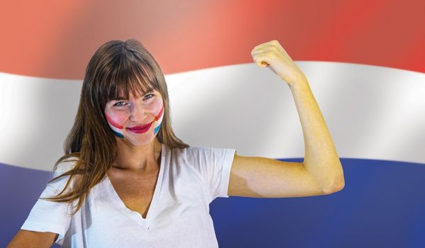  a woman with the ducth flag painted on her face flexing in front of a dutch flag
