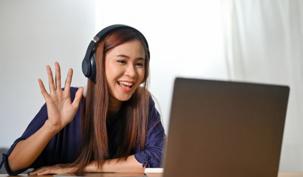 an online tutor waving to her students via computer screen