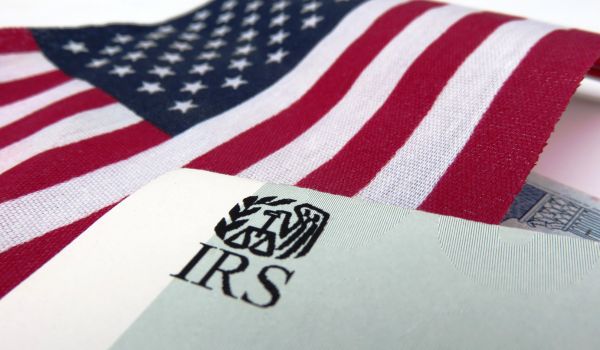 an american flag in the background with an IRS paper in the foreground representing fbar filing for expats living abroad