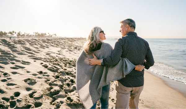 a retired couple walking on the beach