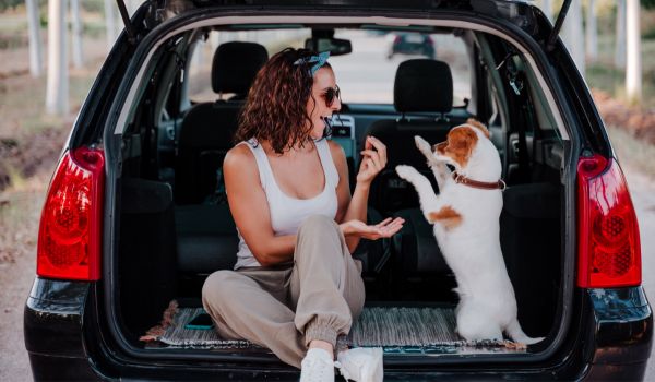 a woman and her dog in the trunk of a car she owns