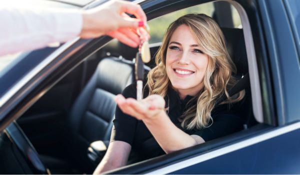 a woman in a car getting handed the keys after buying it using classifieds for cars in the netherlands