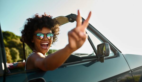 a woman giving a peace sign after buying a car using classifieds for cars in the nethjerlands