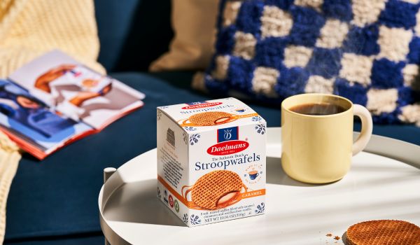 a box of daelman's stroopwafels next to a cup of coffee