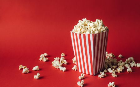a bucket of popcorn against a red background
