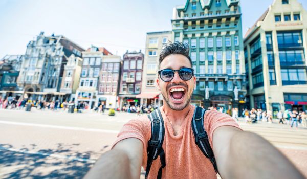 a happy Netherlands tourist taking a selfie in amsterdam