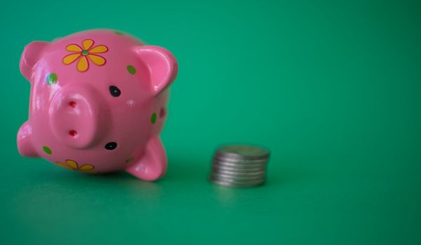 a pink piggy bank tipped over against a green background