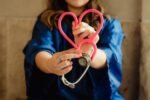 a woman holding a stethoscope in the shape of a heart