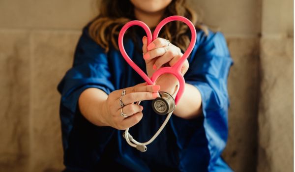 a woman holding a stethoscope in the shape of a heart