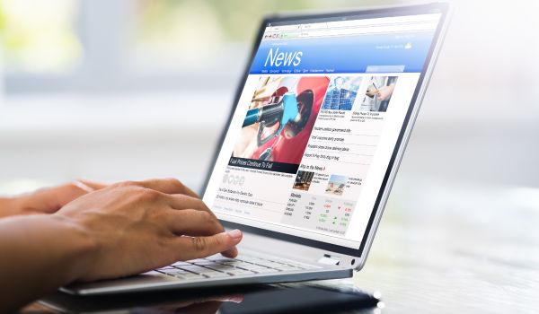 a computer showing news in the netherlands and a mans hands
