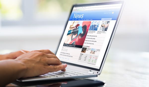 a computer showing news in the netherlands and a mans hands