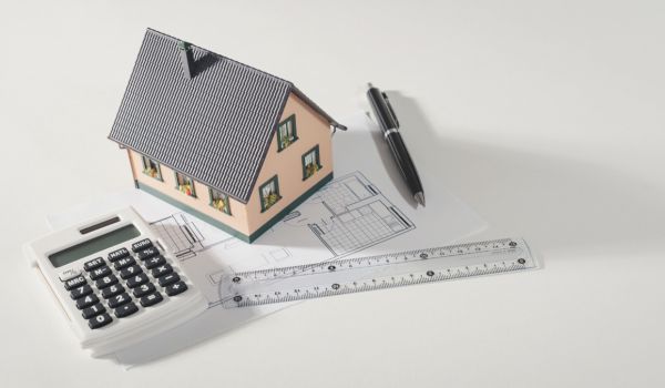 a flatlay of a house model with a ruler and calculator