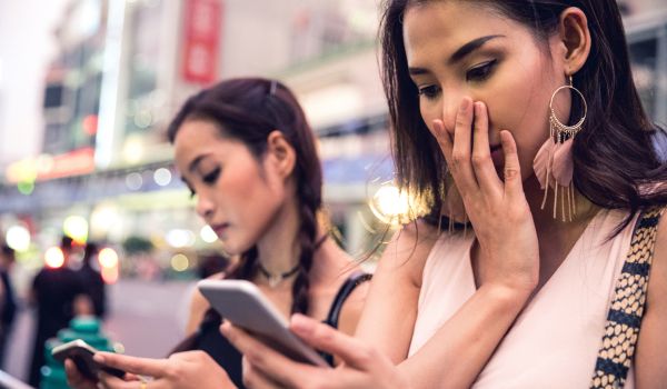 two women staring at their phons after receiving bad news