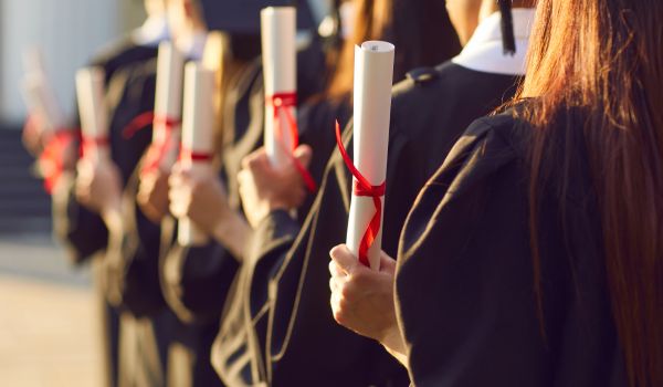 a row of recent graduates holding their degrees