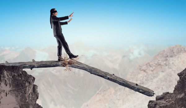 a blindfolded woman walking on a broken log