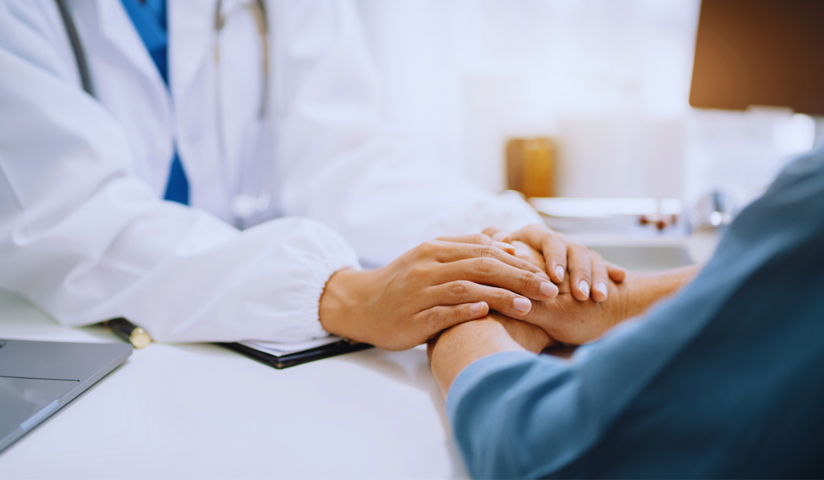 a doctors hands reassuring an elderly patient