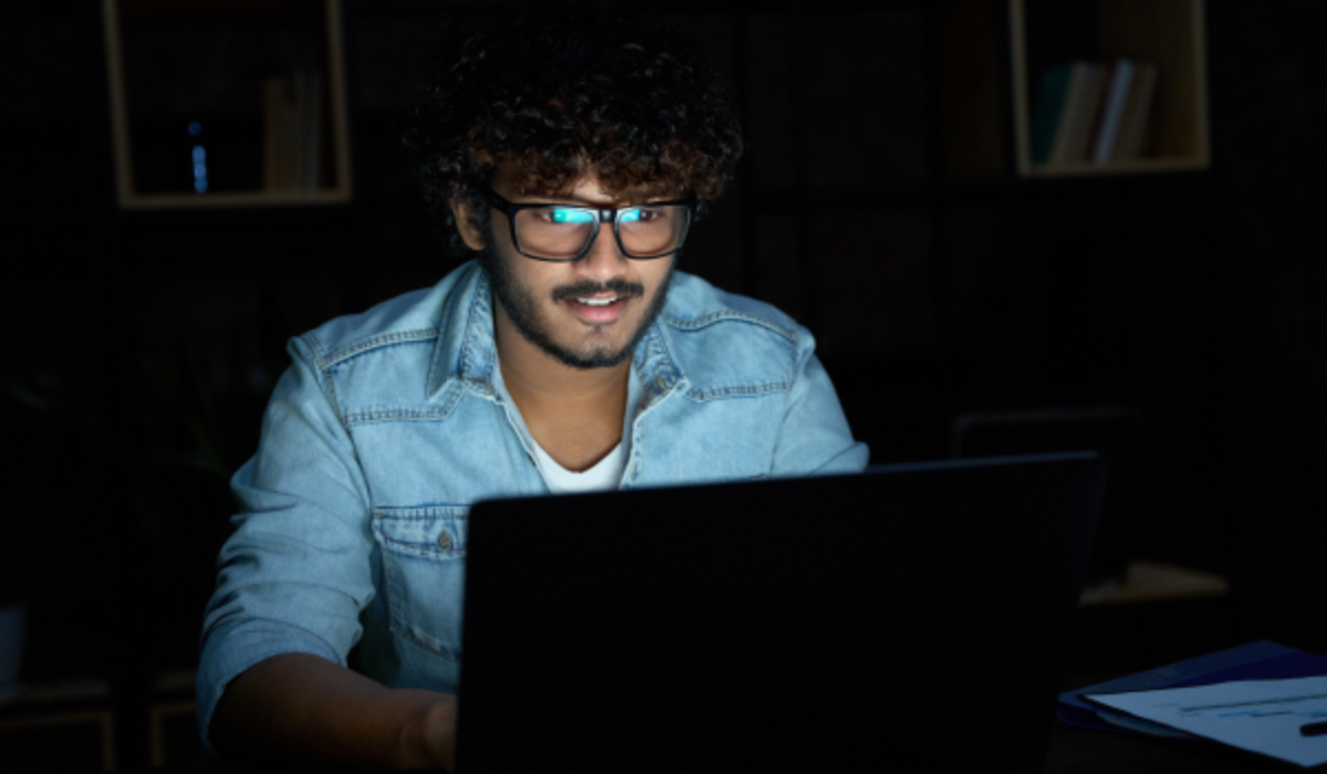 An Indian man working on his laptop in the dark