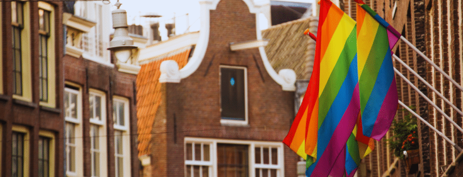 Two pride flags hanging outside a building in Amsterdam