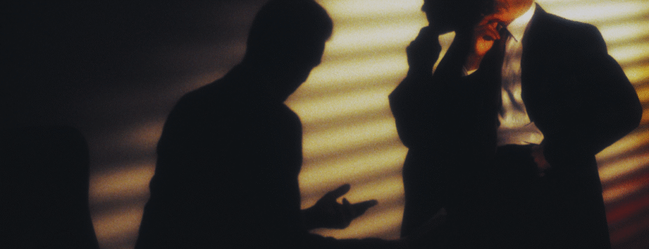 Two businessmen speaking in secret
