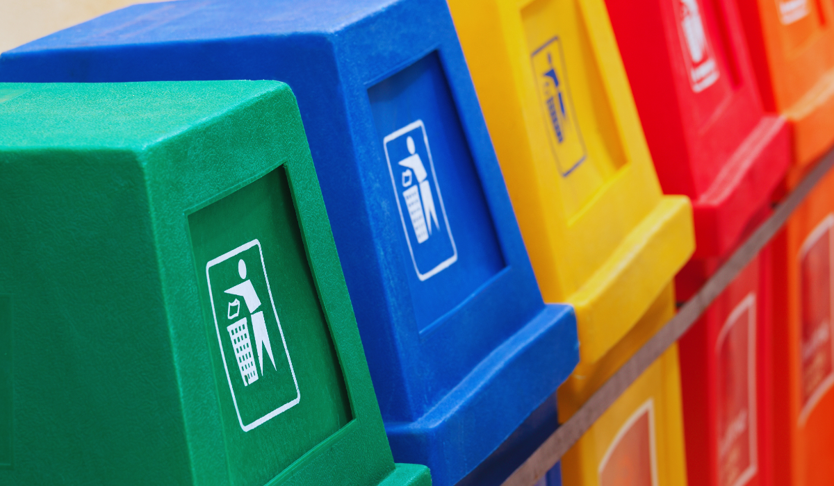 a row of multi-colored recycling bins