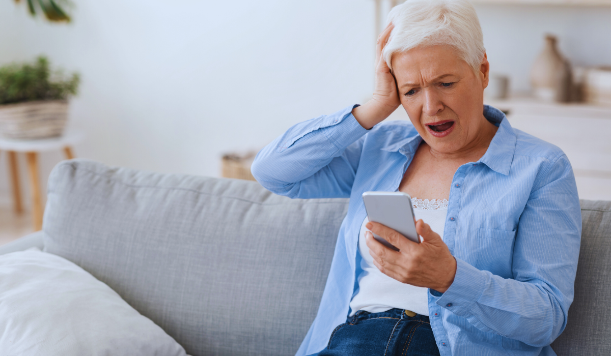 An elderly woman looking at her mobile phone is disbelief