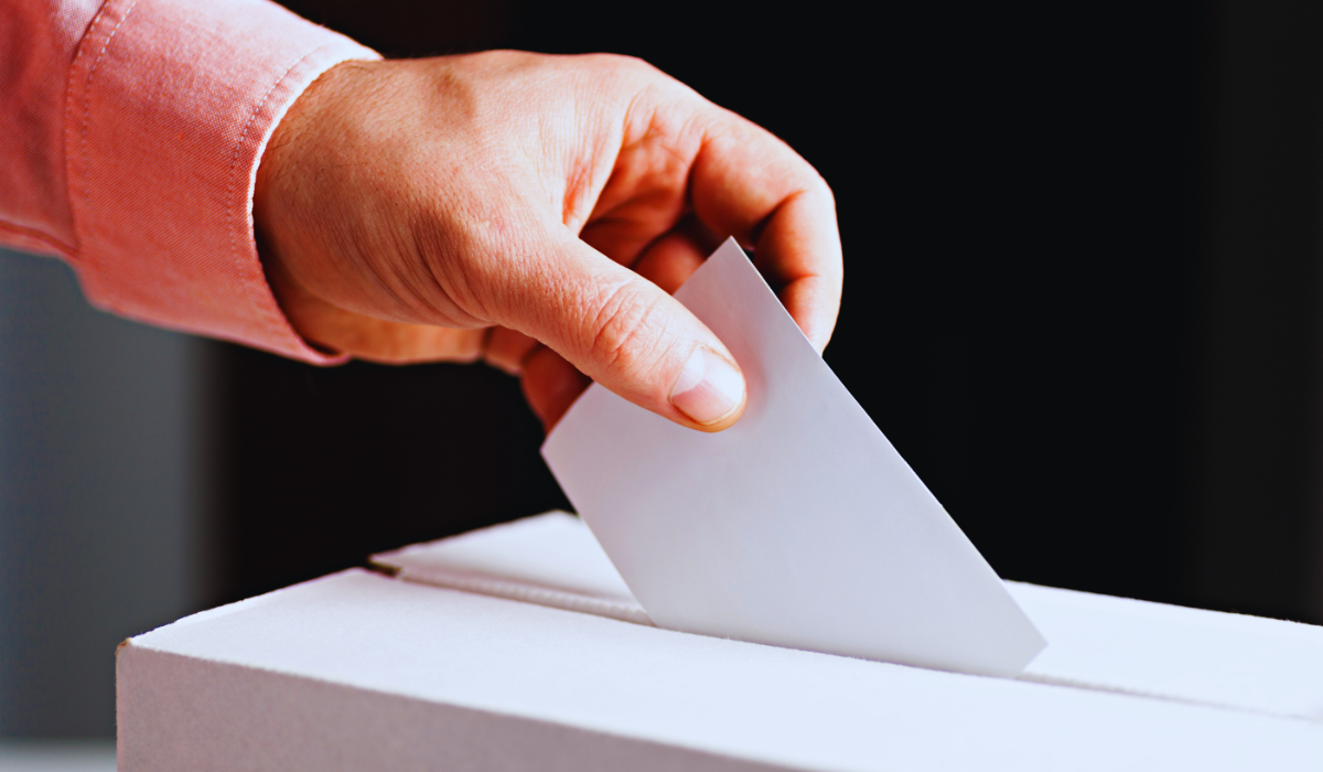 a hand dropping a vote in the ballot box