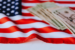 An American flag with a stack of dollar bills resting on it