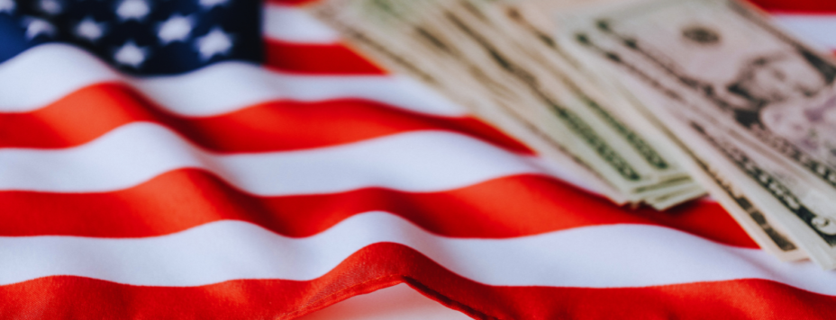 An American flag with a stack of dollar bills resting on it
