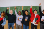 A group of students raising their hands after passing the Dutch Inburgering 2026