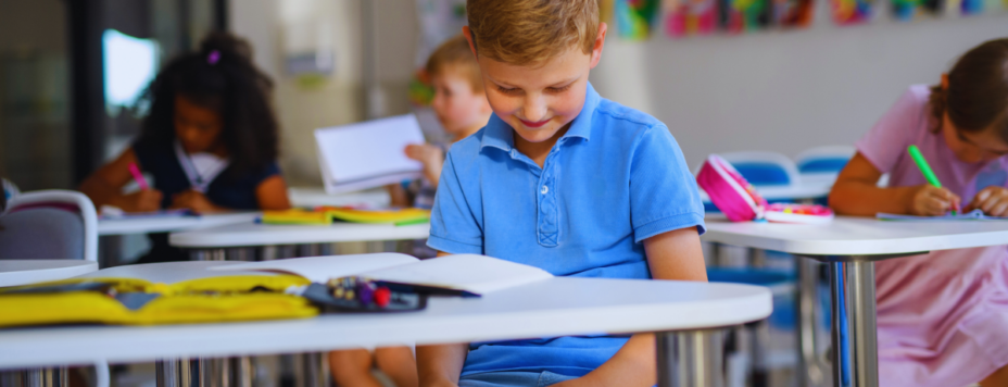 A young Dutch schoolboy distracted by his mobile phone in a classroom