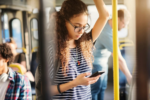 A young woman learning dutch on an app on her phone in the metro
