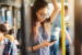 A young woman learning dutch on an app on her phone in the metro