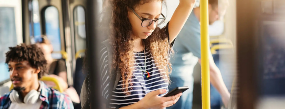 A young woman learning dutch on an app on her phone in the metro