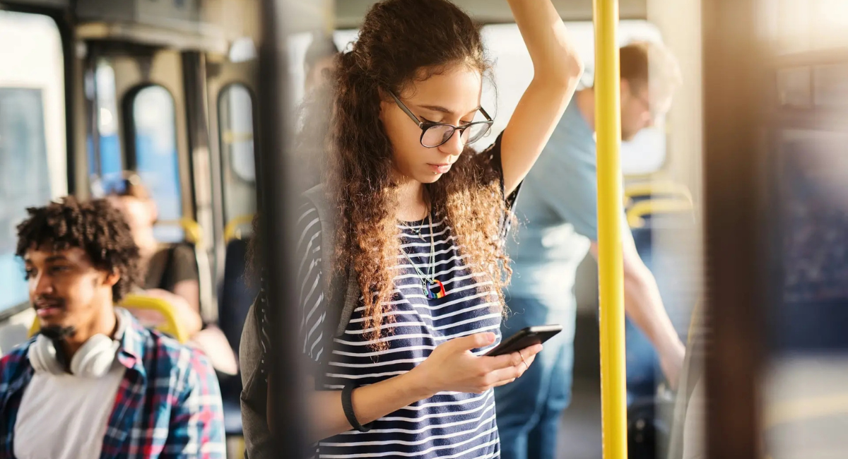A young woman learning dutch on an app on her phone in the metro
