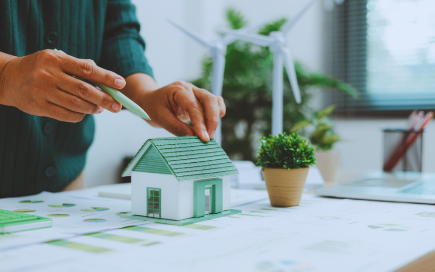 eco-friendly house model with solar panels and business charts on a desk